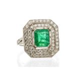 An emerald and diamond platinum ring, comprising an emerald cut emerald rub-over set to the