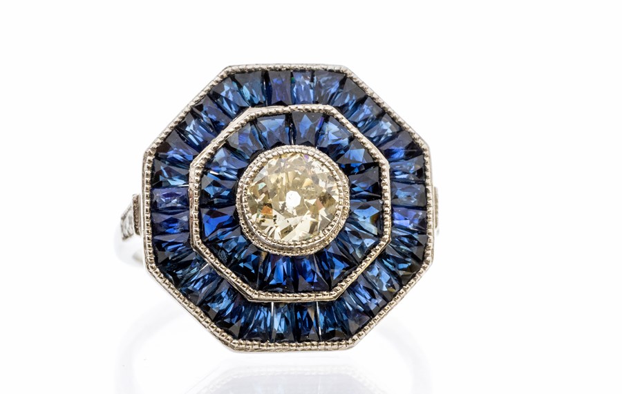 An Art Deco style sapphire and diamond platinum set cocktail ring, comprising a central rub-over set