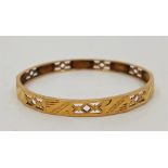 A precious yellow metal faceted bangle, pierced and engraved, external width approx. 62mm, (yellow