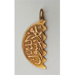 A Middle Eastern 18ct. gold pendant/charm, of demi-lune form, cast with calligraphy, impressed "