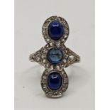 A precious white metal, sapphire and diamond ring, set central circular cabochon sapphire with