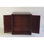 An early 20th century mahogany coin cabinet, having paneled doors enclosing thirteen coin drawers,