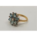 An 18ct. gold, light blue stone and diamond cluster ring. set central round brilliant cut diamond