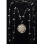 A precious white metal, diamond and pearl pendant necklace, having circular pendant with brushed