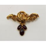 A precious yellow metal and carbuncle set brooch, fashioned as a twisting grape vine with textured