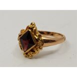 An antique precious yellow metal and garnet set ring, having scrolling mount with central lozenge