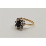 A 9ct. gold, sapphire and clear stone cluster ring, set oval cut sapphire to centre bordered by