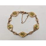 An Art Nouveau 9ct. gold and peridot set bracelet, having navette form pierced links each with