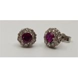 A pair of 9ct. white gold, ruby and diamond cluster stud earrings, set round cut ruby to centre,