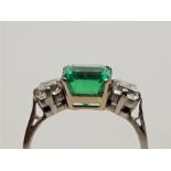 A platinum, Columbian emerald and diamond ring, four claw set octagonal cut emerald to centre (