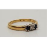 An 18ct. gold, sapphire and diamond ring, set single rond cut diamond flanked by round cut