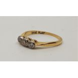 An 18ct. gold and platinum three stone diamond ring, having three graduated round old cut diamonds