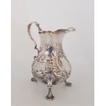 A Victorian silver cream jug, makers mark rubbed, assayed London 1838, repousse rural scenes to side