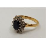 An 18ct. gold, sapphire and diamond ring, set oval cut sapphire bordered by round cut diamonds. (