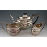 A Geo III style, matching but composite, three piece silver tea set with bright cut ogee body.