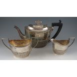 A late Geo III style matching but composite, three piece silver tea set with half reeded bodies.