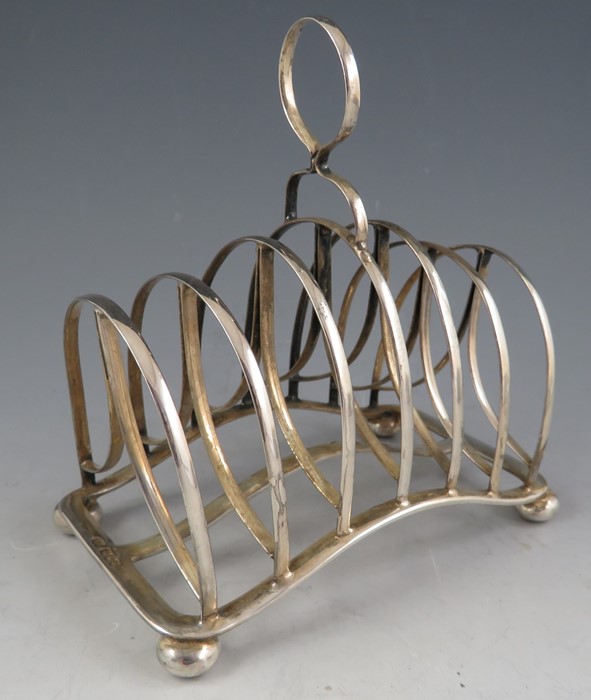 A late Victorian silver six section toast rack of unusual arched form with simple loop handle and