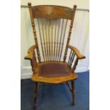 A late 19th century American spindle back oak open arm chair with carve cresting rail. Raised on