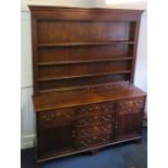 A George III oak dresser fitted two cupboard doors and a central bank of drawers with simple rack