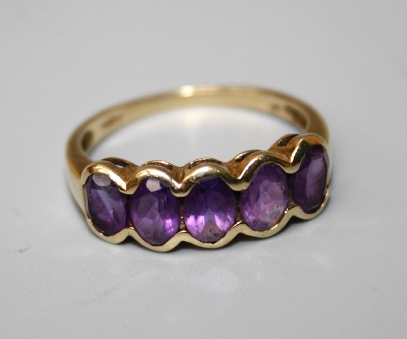 A 9ct gold ring set with five amethysts in a rub-over mount. 2 grms, Size Q.