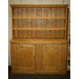 A 20th century pine tall dresser, the rack with two open shelves, the base with a pair of cupboard