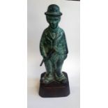 A patinated bronze figure of Charles Chaplin, standing with oversize boots and walking cane. 23cm