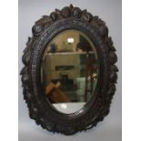 A circa 1900 oak wall mirror with fruit and leaf carved frame and bevelled oval plate. 63 x 46 cms.