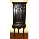 A Victorian carved oak corner cupboard, with a florally decorated panel door, on a cabriole leg