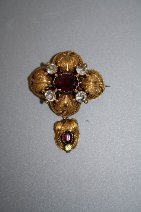 A Victorian yellow gold textured gold brooch, claw set oval cut garnet with further garnet to the