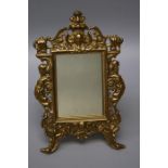 A gilt metal easel mirror decorated with caryatids and masks around a plain rectangular plate. 27
