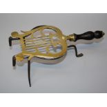 A Geo.III brass lyre form trivet with turned wood handle and wrought iron superstructure.