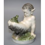 A Royal Copenhagen porcelain figure of a young faun regarding a frog on his knees.Designed by