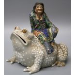 A 20th century Japanese porcelain box and cover modelled as a robed man seated upon a giant toad
