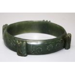 A Chinese spinach jade bangle with cicada detail. 9 cms diameter.
