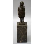 After Bergman, a cast bronze figure of a boy wearing a raincoat and boots with hands in pockets on a