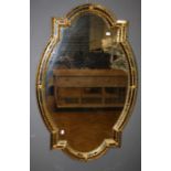 An ornate Venetian style wall mirror of shouldered oval form with beaded gilt slip. 114 x 72 cms.