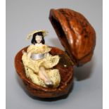 A walnut shell box containing a miniature bisque doll with lace costume.