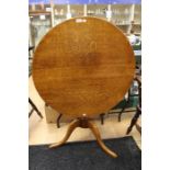 A George III style oak tilt-top tripod table, traditionally made, the circular top raised on a