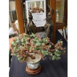 A reproduction Chinese glass bonzai tree, in green planter, on stand, along with two cast figures