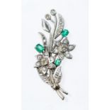 A diamond and emerald spray 18ct white gold  brooch, comprising two daisy heads each one rub over