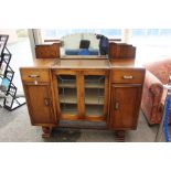 An Art Deco oak mirror backed sideboard, fitted with two glazed doors to centre, two panelled