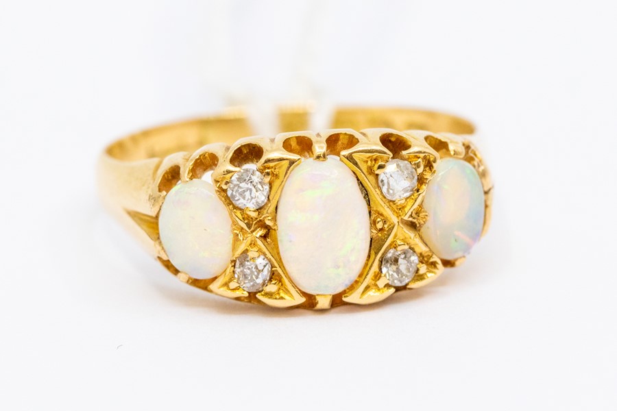 A Victorian opal and diamond ring 18ct gold, comprising three oval opals with alternate diamond