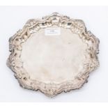 An Edwardian silver salver, pie crust rim on three scroll feet, by Barker Brothers, Chester, 1907,