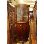 A late 19th Century or later two-tier floor standing bow fronted corner cupboard, later marriage