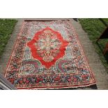 A medium sized hand knotted woollen rug, with stylised floral decoration on a red ground, blue