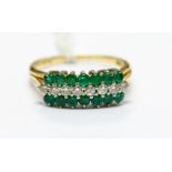 An emerald and diamond 18ct gold cluster ring, comprising a central row of  eight brilliant cut