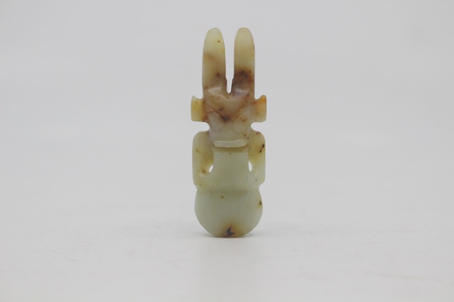 A Chinese pale celadon and russet jade amulet in the neolithic style, Qing Dynasty, of semi-