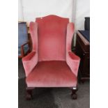 A George II style 1920s pink upholstered wing chair, raised on claw and ball feet, 113cm high,