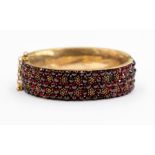 A Victorian Bohemian garnet and gilt metal bangle, comprising round cut garnets and gilt cluster