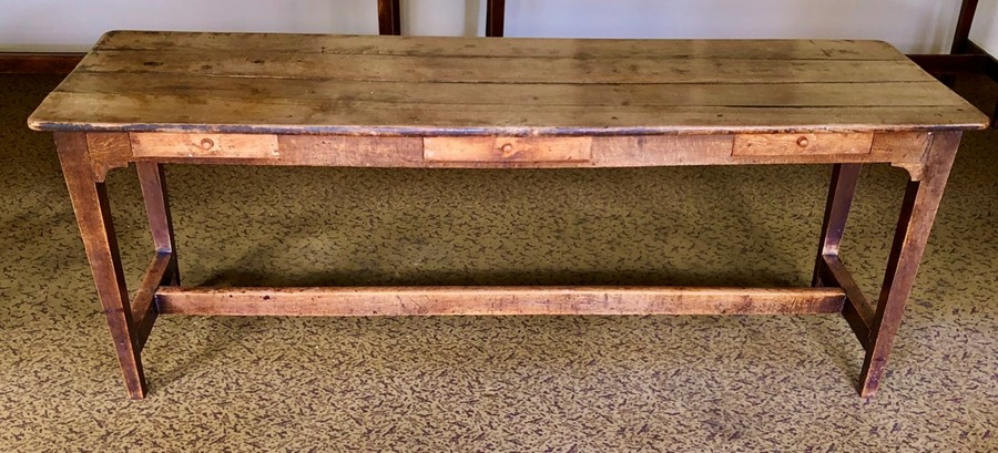 An early 20th Century oak farmhouse kitchen table, three planked top above three single frieze